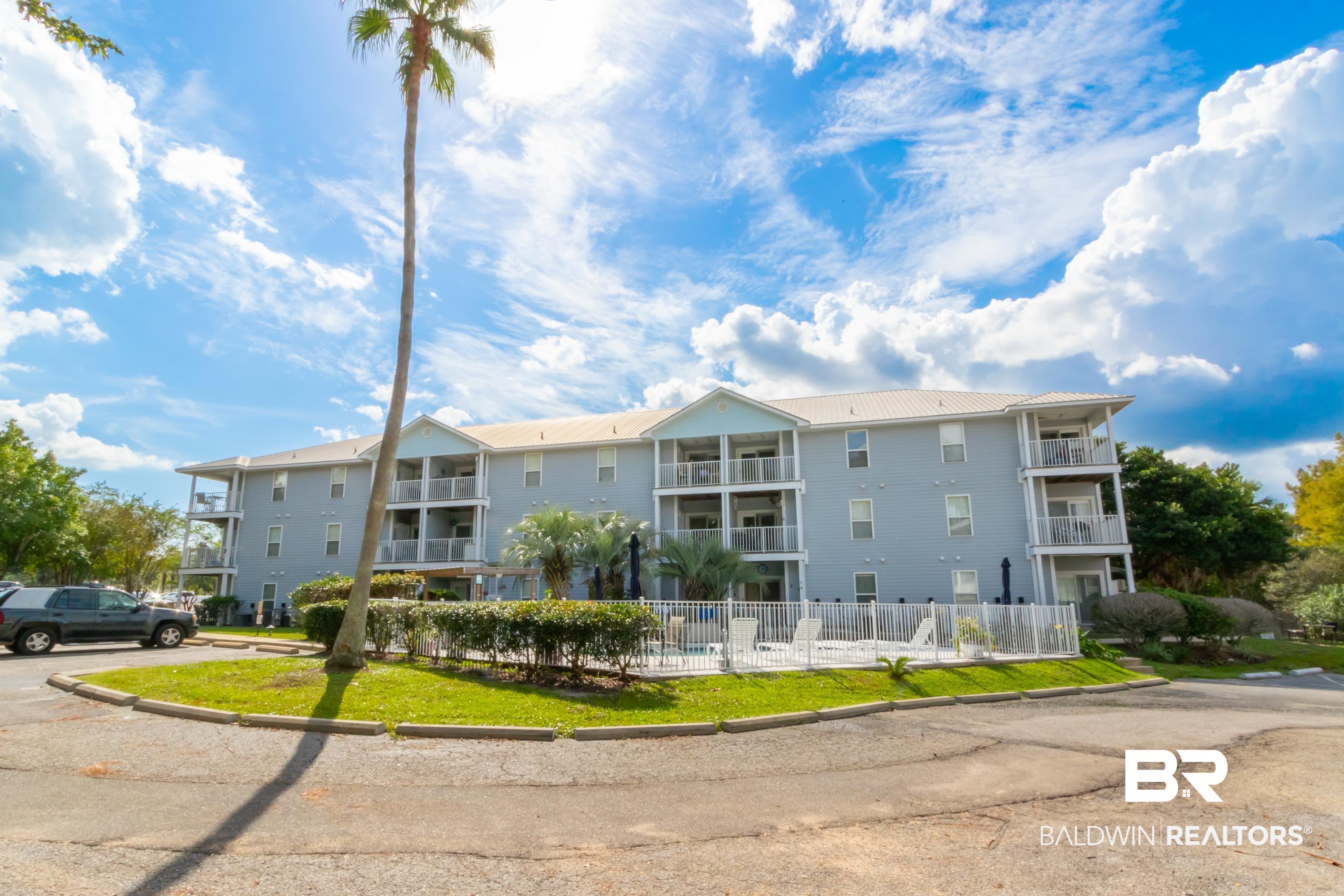 25957 Canal Road, Unit 208 Orange Beach, AL 36561 - Photo 23 of 28 Multi-story building featuring light blue siding, multiple private balconies, and a white metal roof