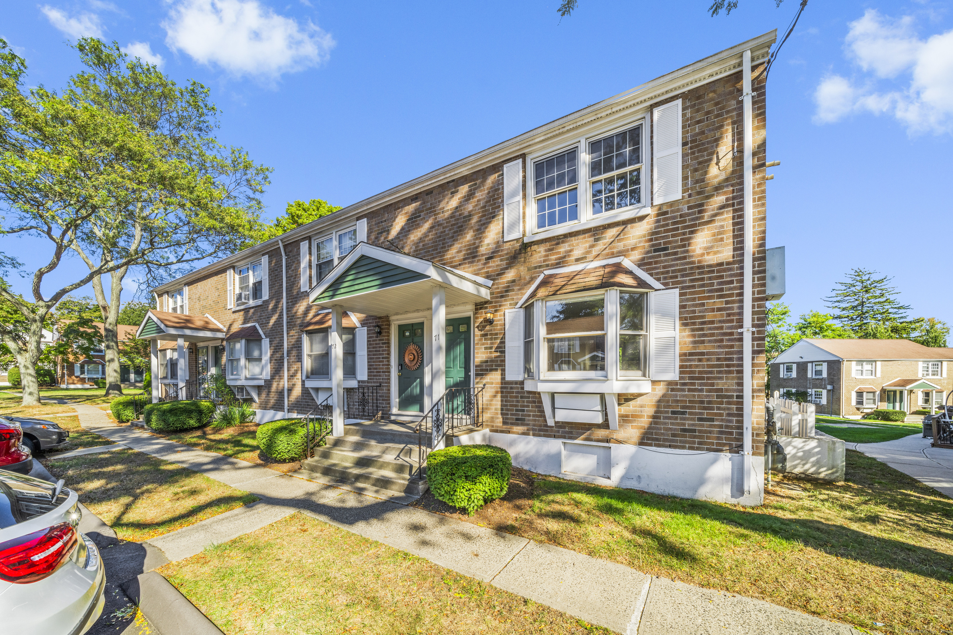 240 Sunnyridge Avenue, Unit 71 Fairfield, CT 06824 - Photo 1 of 1 a view of a brick house with many windows plants and large tree