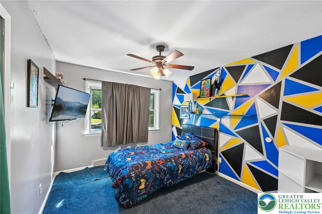 2649 Nottingham Road Bethlehem, PA 18017 - Photo 20 of 49 A well-lit bedroom with a vibrant geometric accent wall and a practical ceiling fan for comfort.