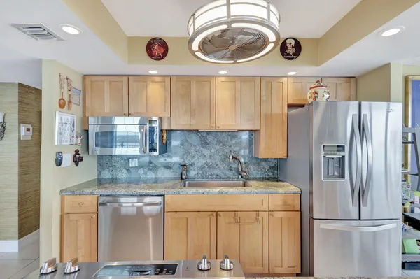 a dining hall with stainless steel appliances granite countertop a table and chairs