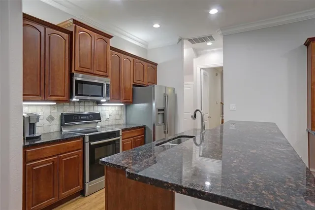 a kitchen with stainless steel appliances granite countertop a sink a stove and a refrigerator