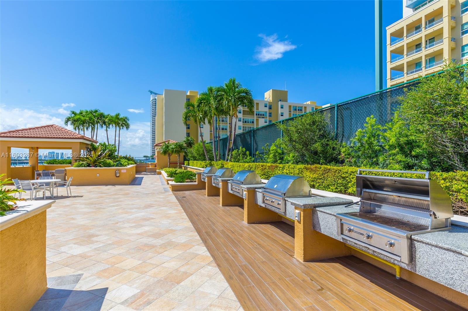 90 Alton Road, Unit 2806 Miami Beach, FL 33139 - Photo 21 of 36 a view of a patio with couches and table and chairs under an umbrella with wooden floor