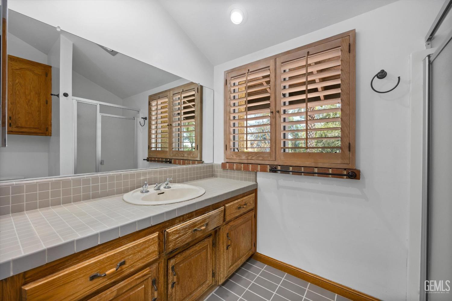 Undisclosed Address Bakersfield, CA 93306 - Photo 47 of 75 a bathroom with a granite countertop sink a large mirror and a shower