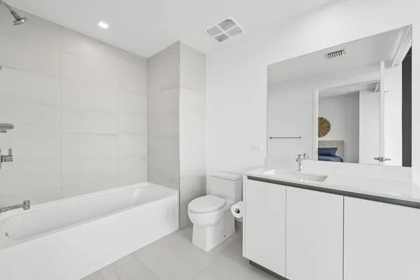 a bathroom with a bathtub shower sink mirror and toilet