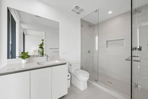 a bathroom with a shower sink vanity mirror and toilet