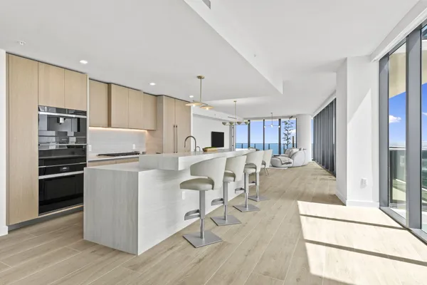 a kitchen with stainless steel appliances kitchen island granite countertop a stove a refrigerator a sink a dining table and chairs with wooden floor