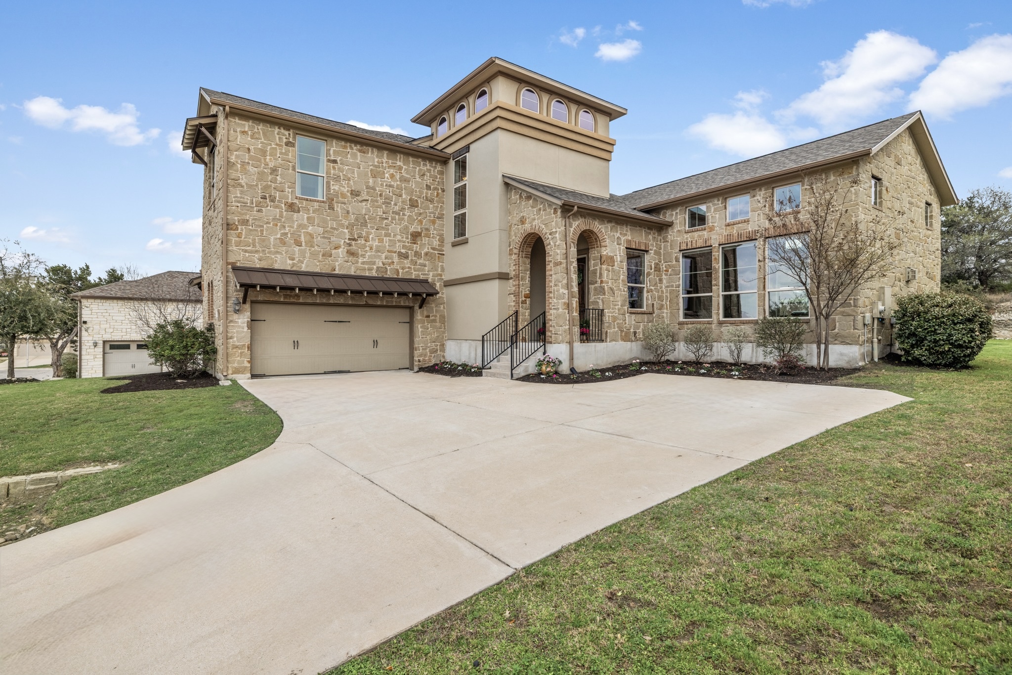 View of front of property featuring stone siding, a garage, a front yard, and driveway