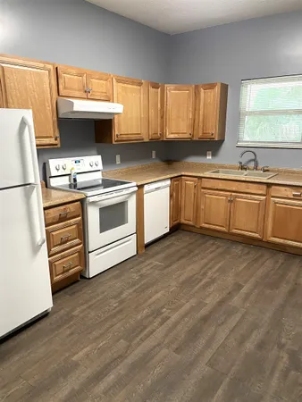 a kitchen with stainless steel appliances a stove a sink and white cabinets with wooden floor
