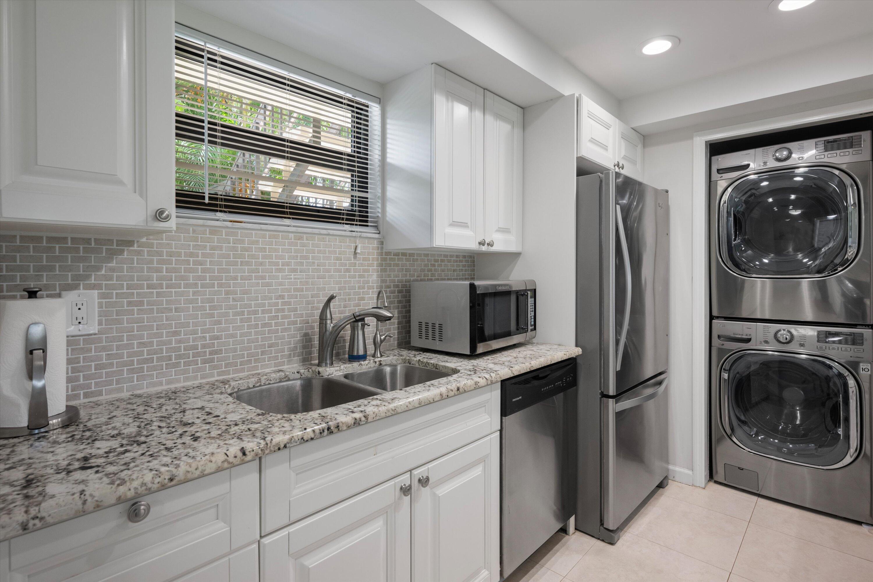 13334 Polo Club Road, Unit 228 Wellington, FL 33414 - Photo 11 of 26 a kitchen with stainless steel appliances granite countertop a sink a washer and dryer