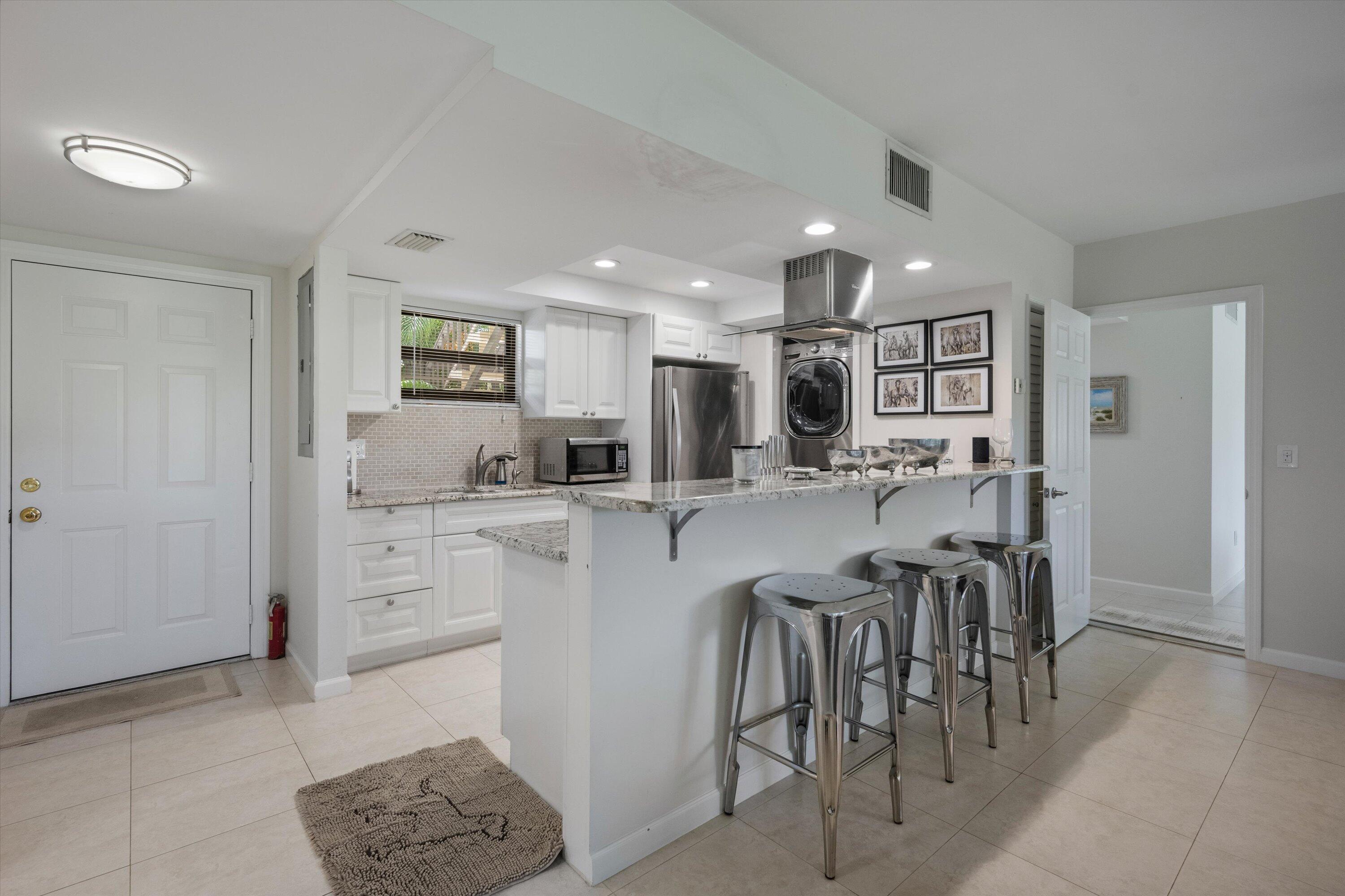 13334 Polo Club Road, Unit 228 Wellington, FL 33414 - Photo 8 of 26 a kitchen with stainless steel appliances kitchen island granite countertop a refrigerator and cabinets