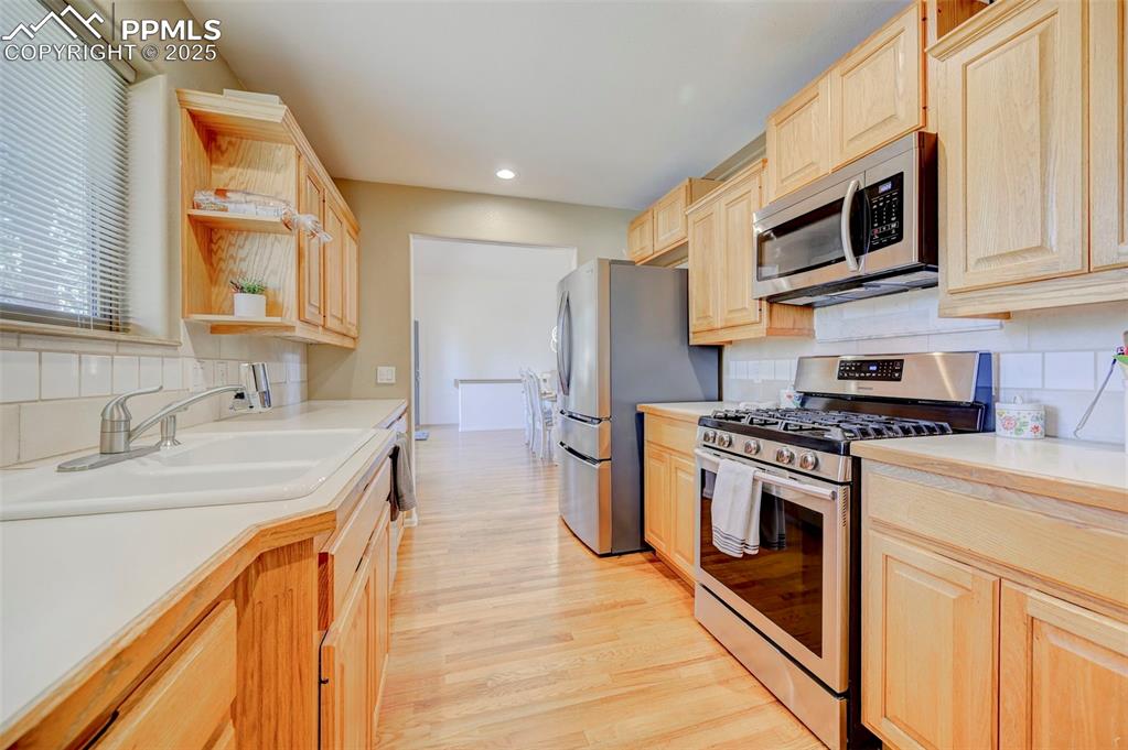 840 West Kelly Road Woodland Park, CO 80863 - Photo 10 of 47 Kitchen featuring light countertops, a sink, backsplash, light brown cabinets, and appliances with stainless steel finishes