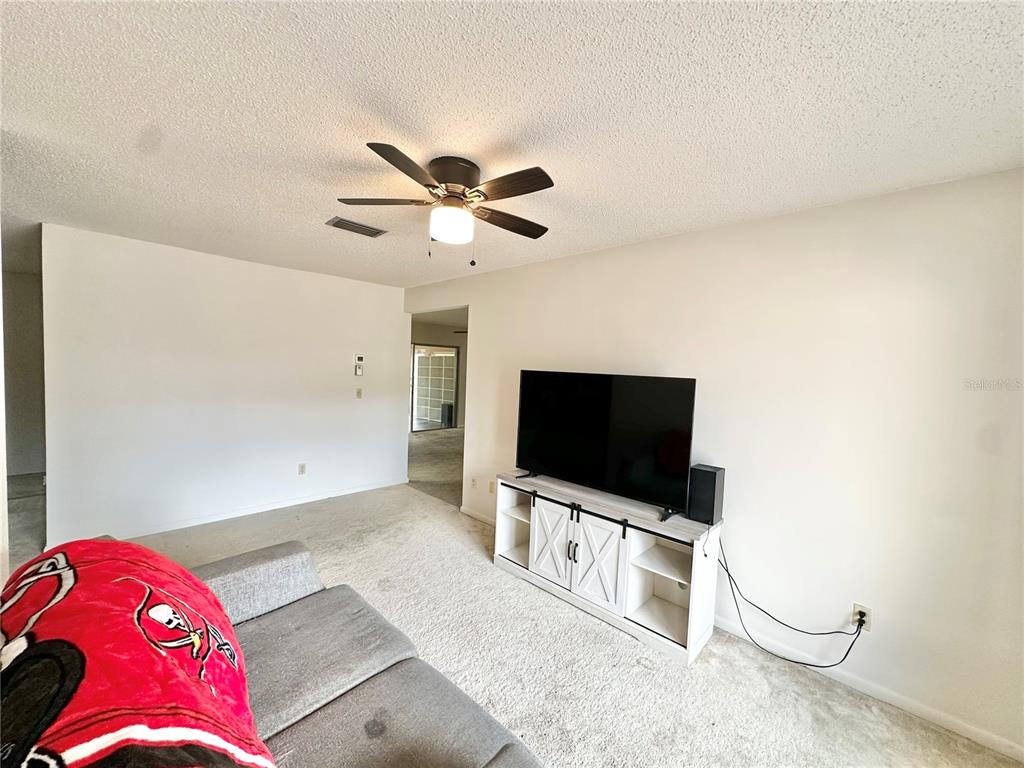 7414 Acorn Circle Spring Hill, FL 34606 - Photo 12 of 50 a living room with a flat screen tv and a ceiling fan