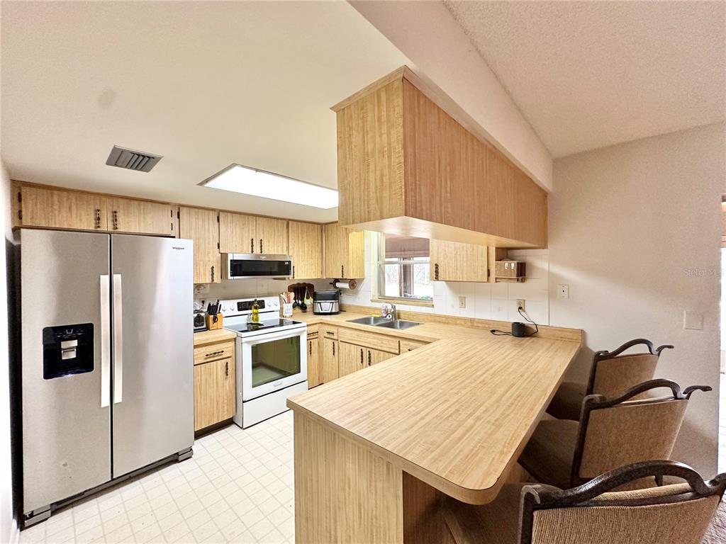 7414 Acorn Circle Spring Hill, FL 34606 - Photo 18 of 50 a kitchen with a refrigerator a stove a sink dishwasher with a dining table and chair
