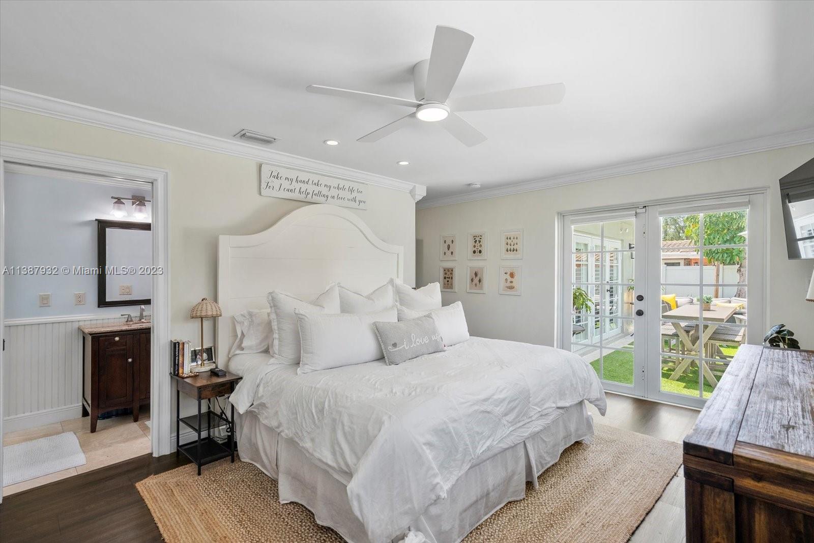 2533 Northeast 21st Terrace Lighthouse Point, FL 33064 - Photo 20 of 45 a spacious bedroom with a large bed and a chandelier