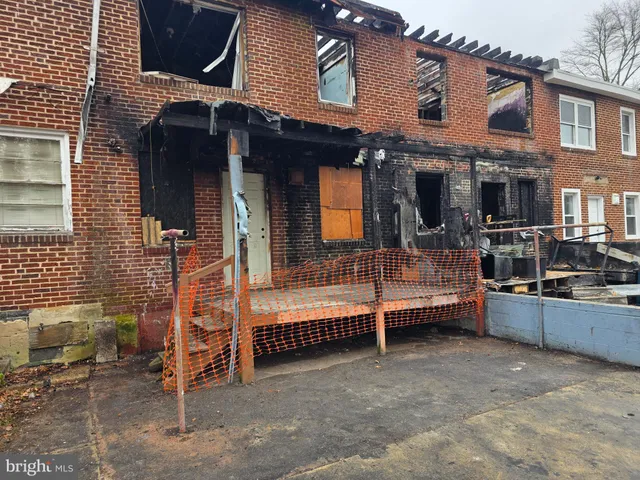 a view of a house with a barbeque and wooden fence