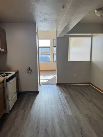 a view of an empty room with wooden floor and a window