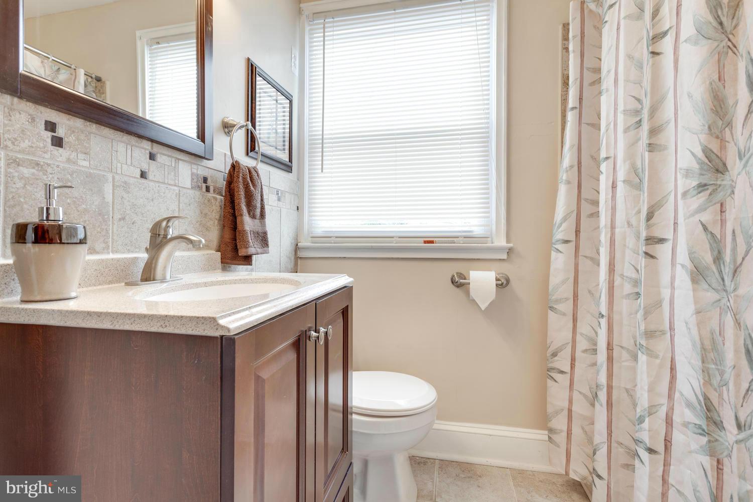 1701 Burnwood Road Baltimore, MD 21239 - Photo 16 of 30 a bathroom with a sink a toilet and a mirror