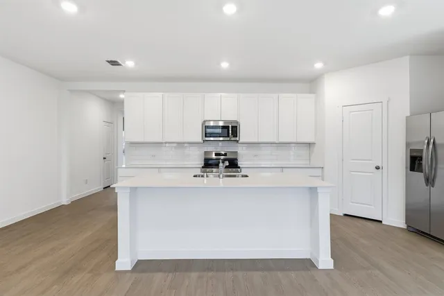 a kitchen with stainless steel appliances granite countertop a stove a sink and a refrigerator