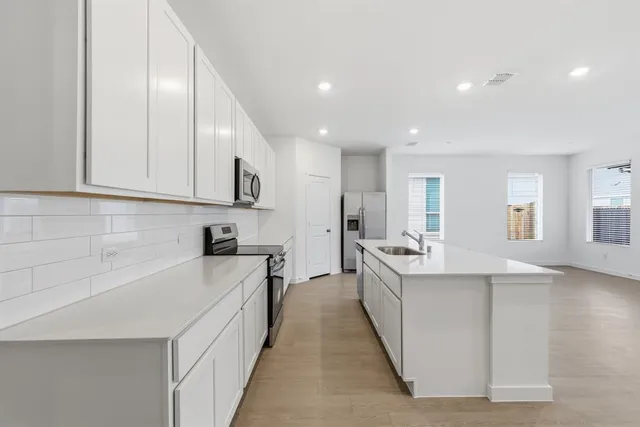 a large kitchen with stainless steel appliances granite countertop a lot of counter space and wooden floor