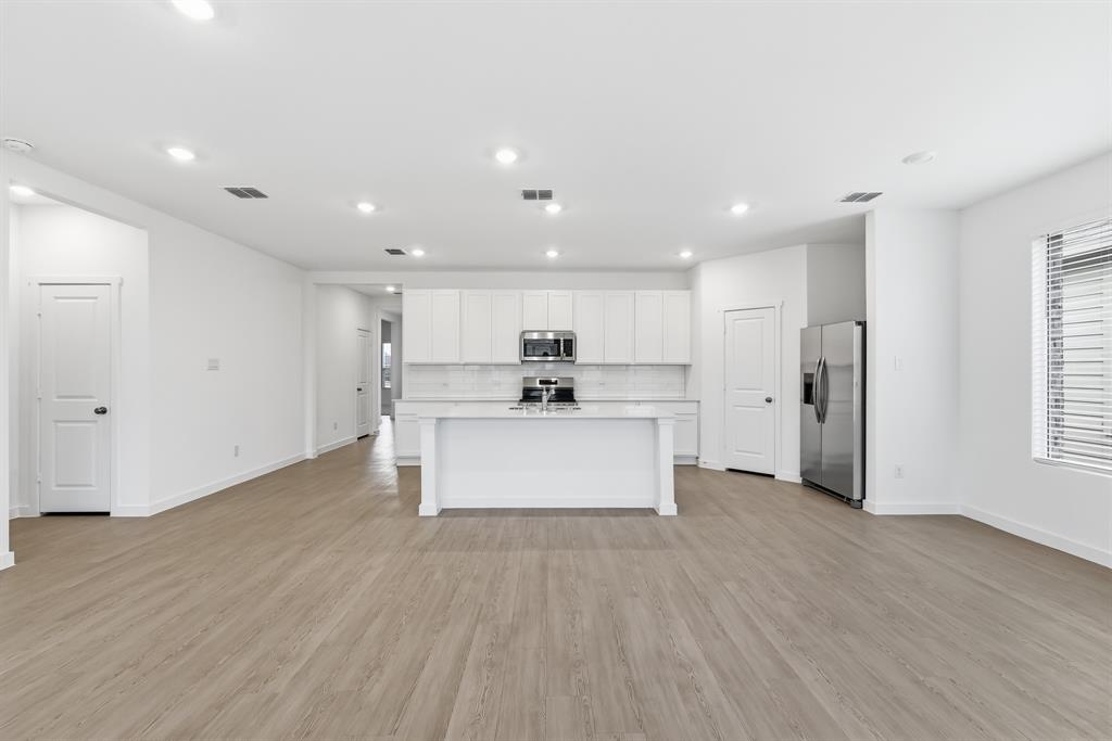 4916 Ascot Way Princeton, TX 75407 - Photo 8 of 39 a view of kitchen with stainless steel appliances kitchen island wooden floors and white walls