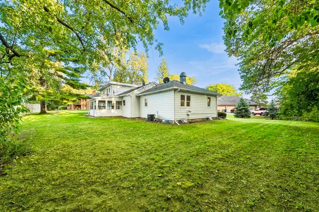 a white house with a big yard and large trees