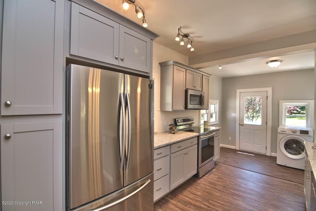 362 Upper Swiftwater Road Cresco, PA 18326 - Photo 18 of 87 a kitchen with stainless steel appliances granite countertop a refrigerator a stove and a sink with wooden floor