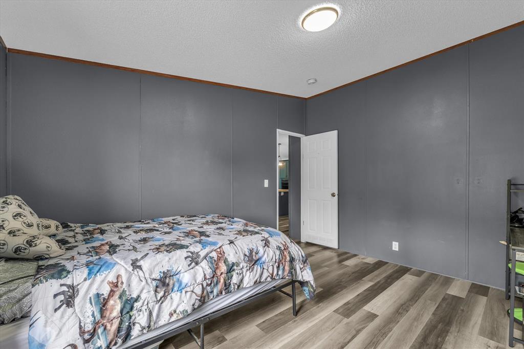 3615 Spring Valley Road Lorena, TX 76655 - Photo 12 of 33 Room featuring wood-finish flooring and grey wall paneling with brown trim