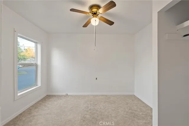 an empty room with closet and a chandelier fan