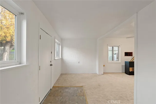a view of empty room with a window and a kitchen