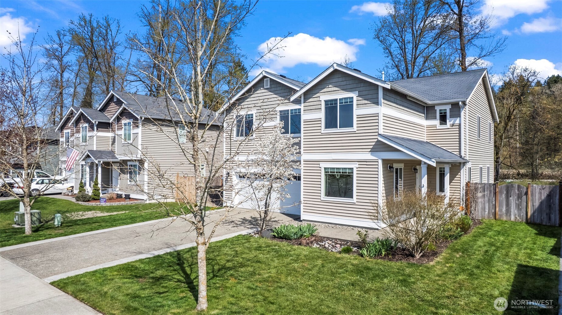 1408 Daffodil Avenue Northeast Orting, WA 98360 - Photo 36 of 37 a view of a white house next to a yard with big trees