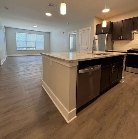 a kitchen with stainless steel appliances granite countertop wooden cabinets a refrigerator a sink a stove a microwave and wooden floors