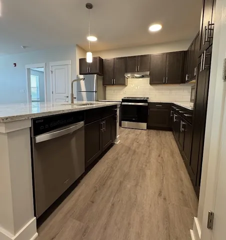 a kitchen with kitchen island a refrigerator and a sink