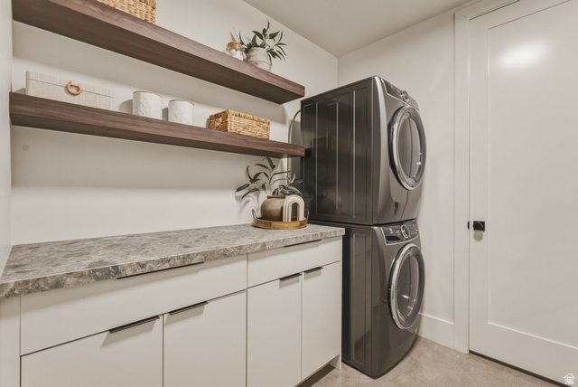 923 North Emery Lane Elk Ridge, UT 84651 - Photo 69 of 101 Modern laundry area featuring a stacked washer and dryer, white cabinetry, a patterned countertop, and dual wood-finish floating shelves