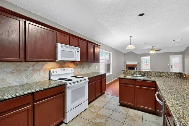 a kitchen with stainless steel appliances granite countertop wooden cabinets a stove a sink and a microwave