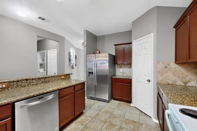 a kitchen with stainless steel appliances granite countertop a refrigerator and a stove