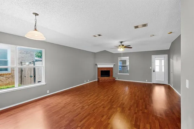 a view of an empty room with window and wooden floor