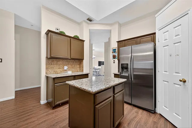 a kitchen with granite countertop a refrigerator and wooden floor