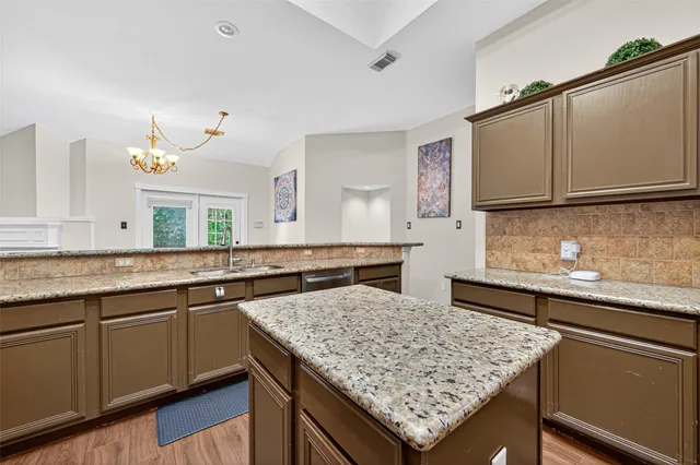 a kitchen with kitchen island granite countertop a sink stove and refrigerator