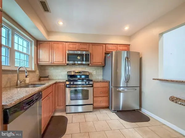 a kitchen with stainless steel appliances granite countertop a refrigerator a stove a sink and a refrigerator
