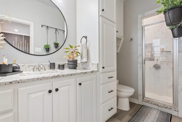 a bathroom with a granite countertop toilet sink and mirror