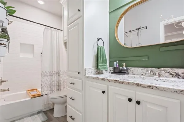 a bathroom with a granite countertop sink vanity mirror bathtub shower and a toilet