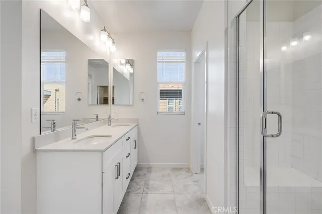 a spacious bathroom with a double vanity sink a mirror and a shower