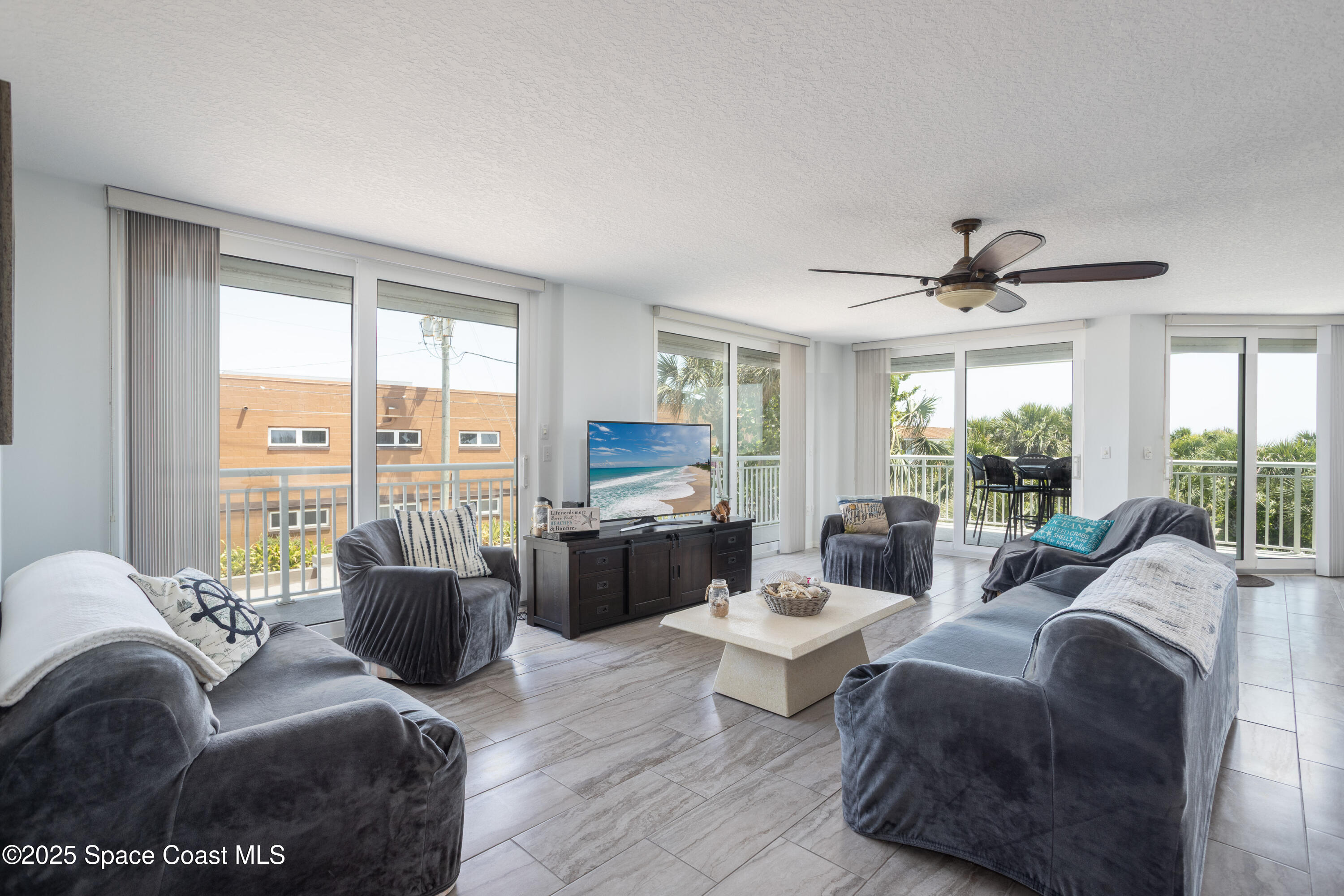 3450 Ocean Beach Boulevard, Unit 201 Cocoa Beach, FL 32931 - Photo 46 of 48 a living room with furniture large windows and wooden floor