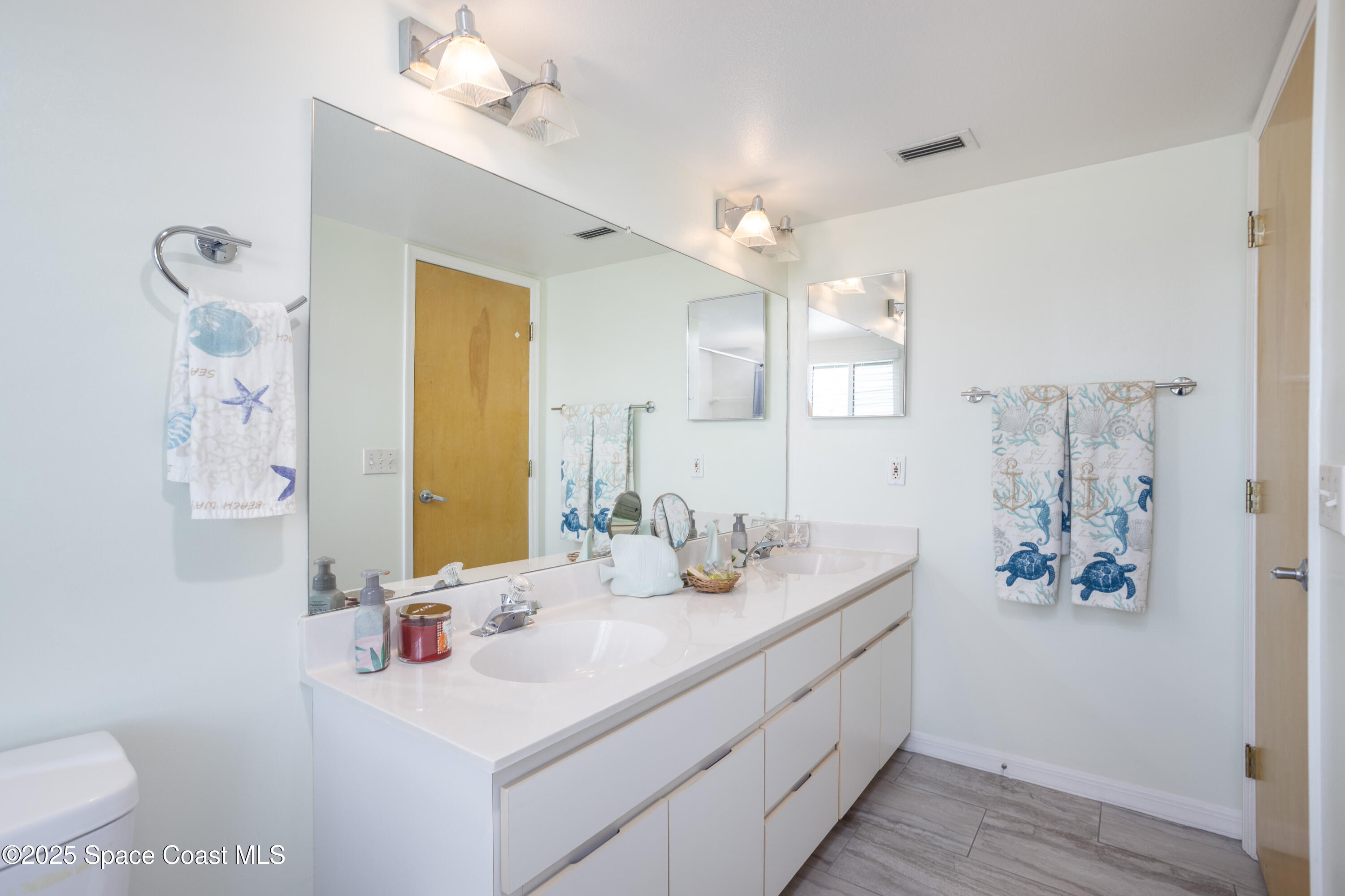 3450 Ocean Beach Boulevard, Unit 201 Cocoa Beach, FL 32931 - Photo 30 of 48 a bathroom with double vanity sinks a toilet a mirror and vanity
