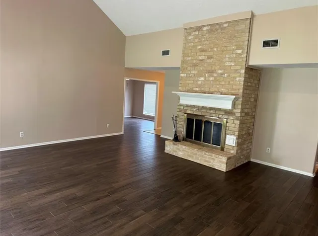a view of a livingroom with wooden floor and a fireplace