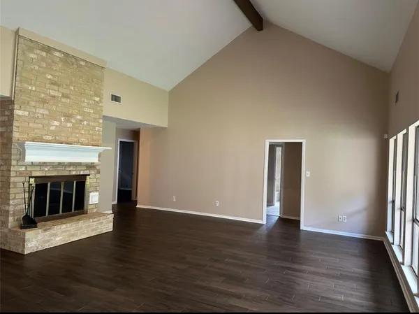 an empty room with wooden floor fireplace and windows