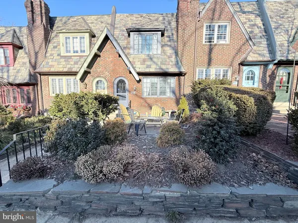 a view of a brick house with a small yard plants and large tree