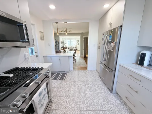 a kitchen with stainless steel appliances a refrigerator a sink a stove top oven a counter space and cabinets