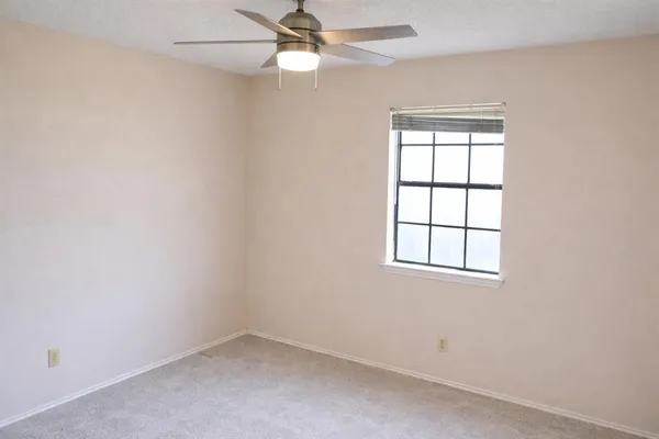 an empty room with a window and ceiling fan