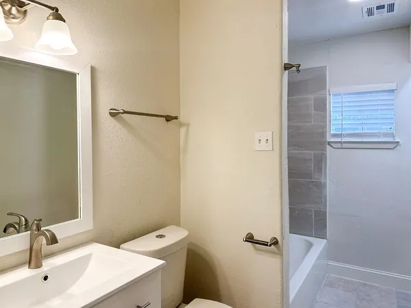 a bathroom with a sink a toilet a shower and a window